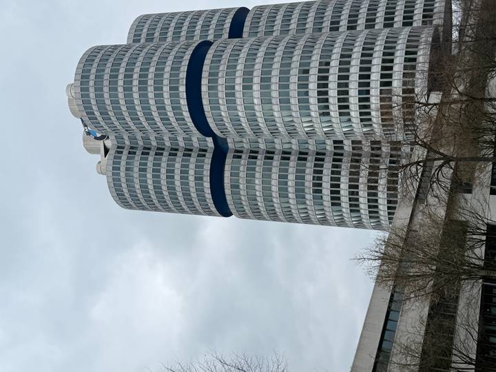 Modern cylindrical BMW Headquarters tower rising against a grey cloudy sky.