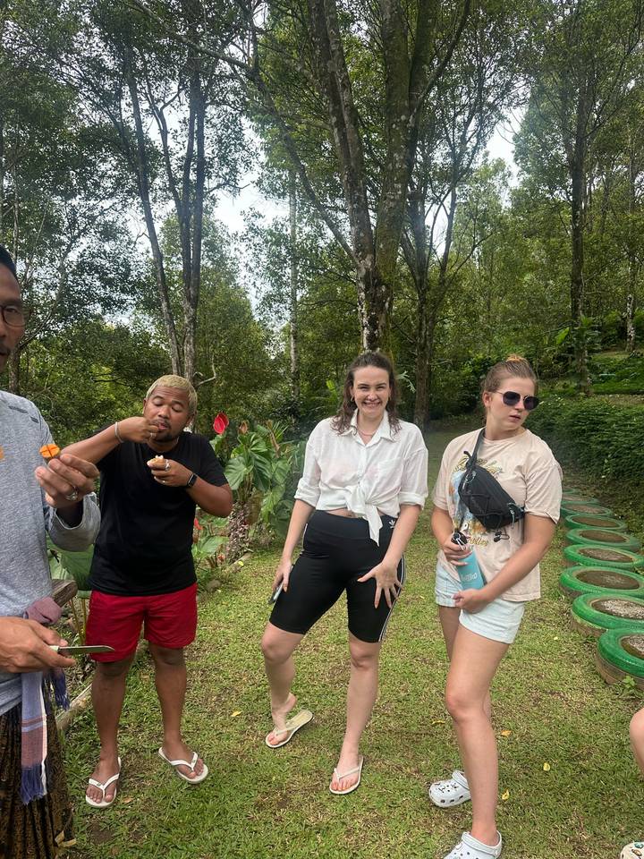 Travellers sample local snacks in a lush garden setting during an outdoor tour stop.
