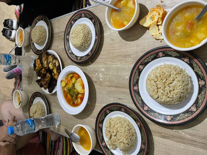 Low table spread with bowls of soup, rice domes and grilled chicken for a desert camp meal.