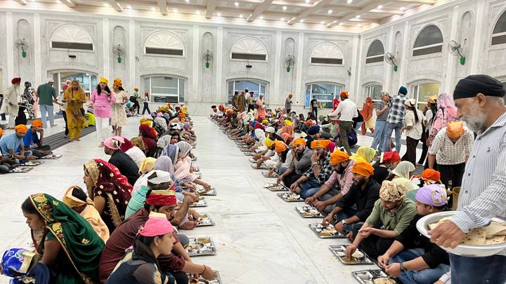 Long rows of pilgrims seated on the marble floor sharing a communal meal in a Sikh langar hall.