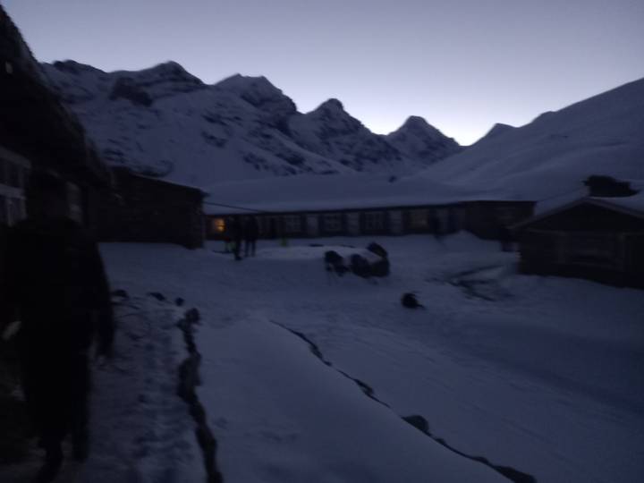 Very dark blurry photo of snow-covered mountain lodge at dusk.