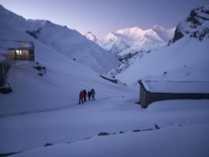 Dark, blurry image of trekkers ascending snowy slope before dawn.
