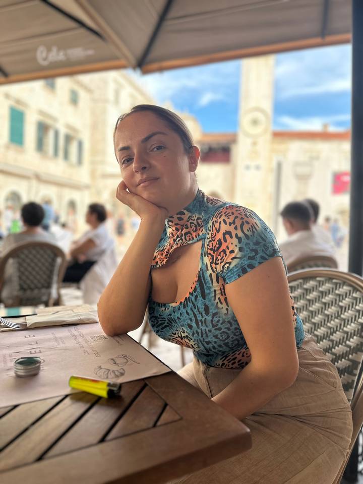 Portrait of woman relaxing at outdoor café in Dubrovnik old town with soft background blur.