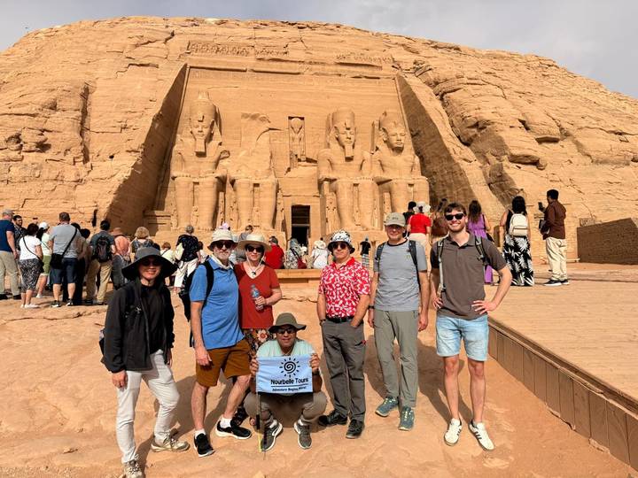 Tour group poses with banner in front of the colossal statues of Abu Simbel temple.