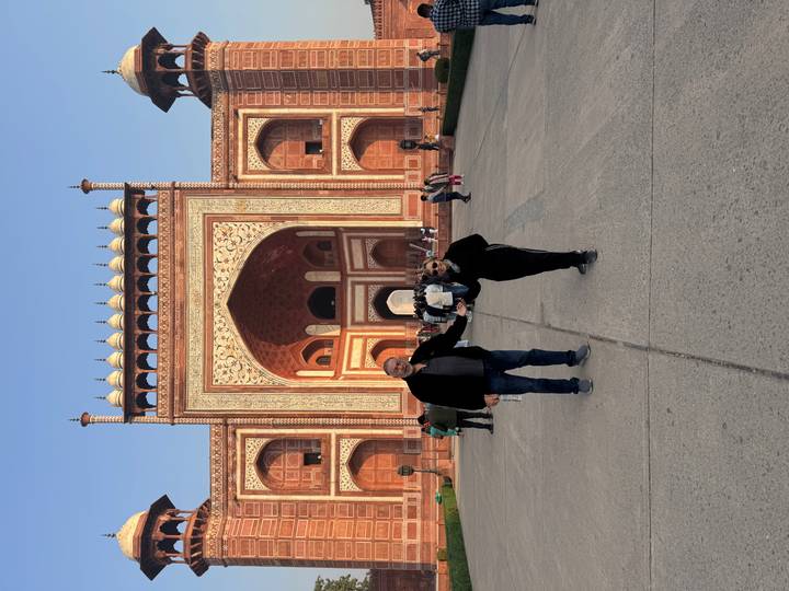 Couple poses on broad pathway before grand Mughal gateway leading to the Taj Mahal.