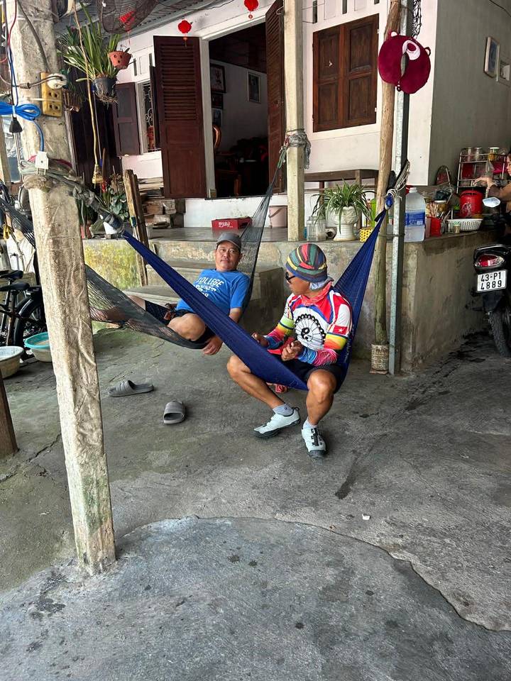Two cyclists relaxing in hammocks at a rustic roadside rest stop.