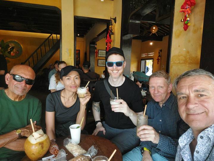 Travel companions enjoying iced coffees inside a cozy café with yellow walls in Vietnam.