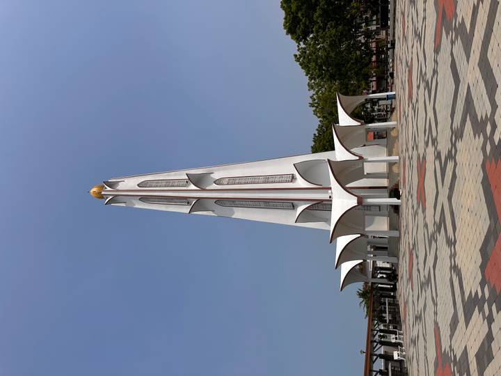 Tall white modern minaret-style tower rising against a clear blue sky in Melaka.