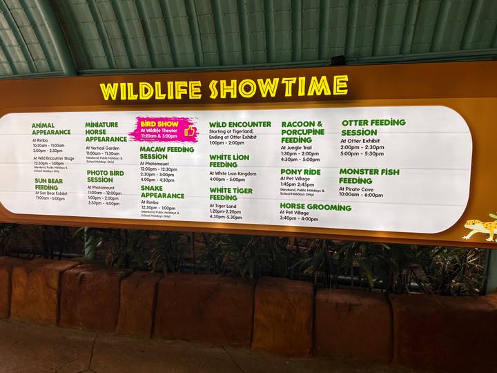 Indoor illuminated schedule board listing wildlife showtimes and feeding sessions.