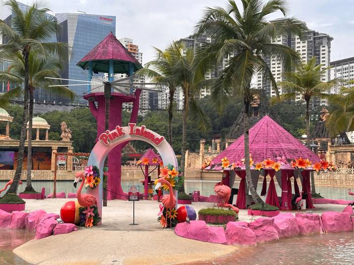 Bright pink 'Pink Island' zone with flamingo statues at a tropical water park.