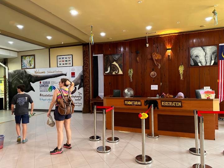 Resort reception area with guests checking in at wooden registration counter.