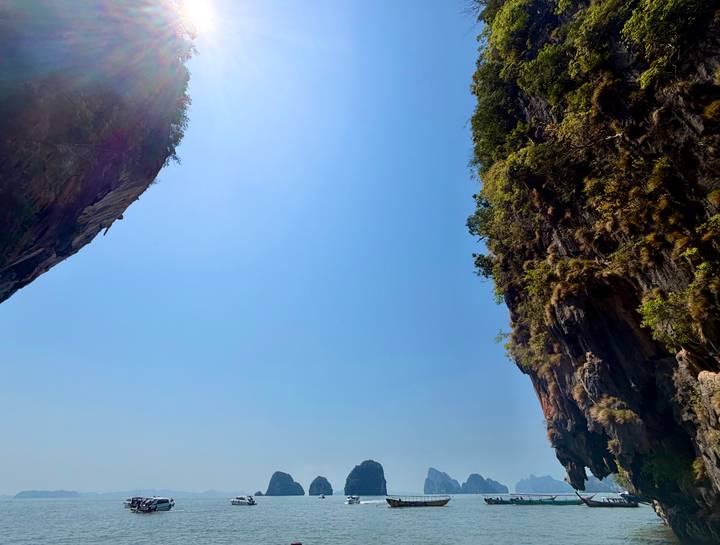 Dramatic vertical view between towering limestone karsts under a bright blue sky in southern Thailand.