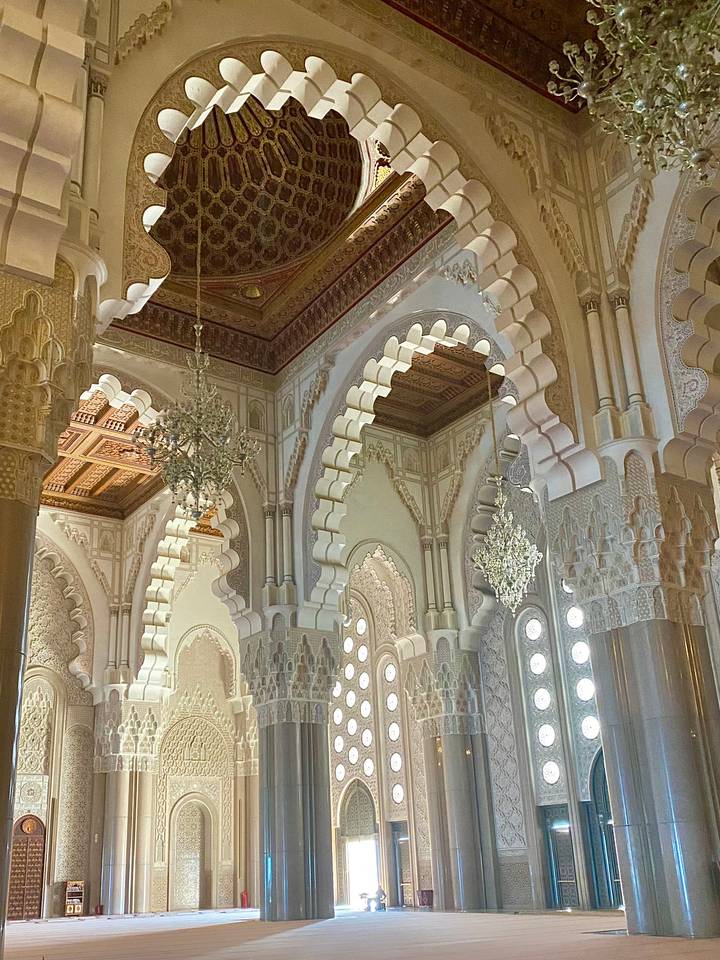 Intricately decorated interior arches and chandeliers of a grand Moroccan mosque.
