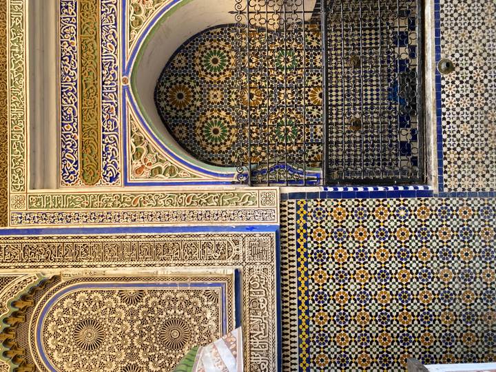 Detailed Moroccan mosaic and carved stucco walls showcasing vibrant patterns and calligraphy.