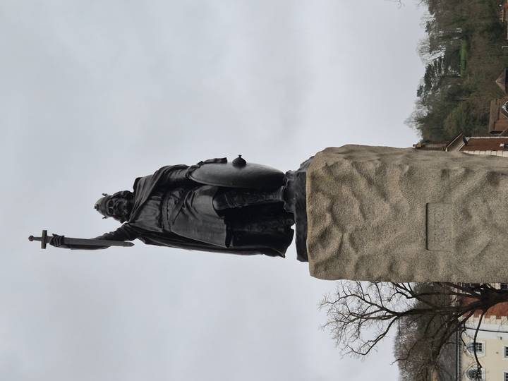 Statue of King Alfred the Great holding a sword aloft, mounted on a tall stone plinth.
