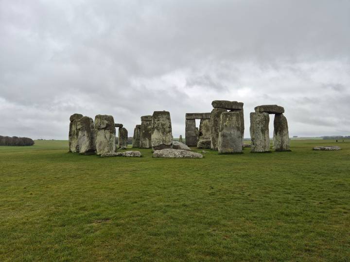 Iconic prehistoric stone circle of Stonehenge standing on open grassland under grey skies.