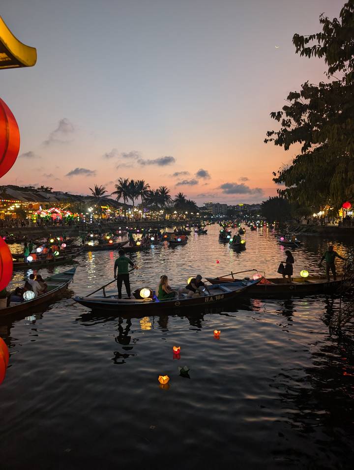 Dozens of lantern-lit boats drifting on Hoi An river at colorful twilight festival