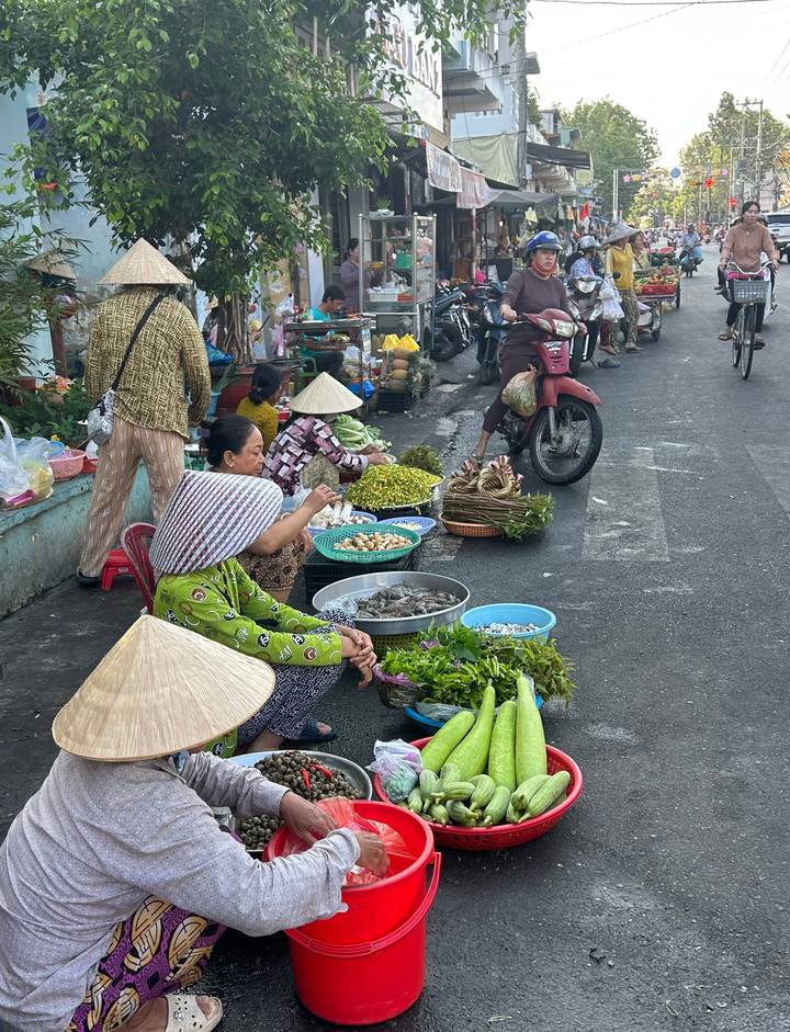 Local women selling fresh produce, seafood and herbs on a roadside market in Vietnam