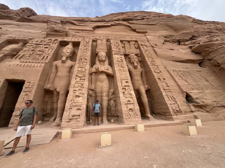 Travelers pose in front of the smaller temple façade at Abu Simbel with colossal statues