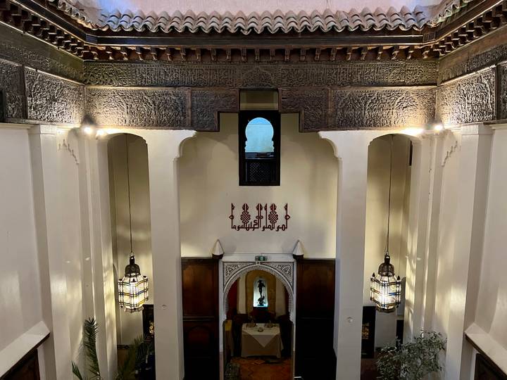 Interior balcony view of a traditional riad with carved wood and Arabic calligraphy