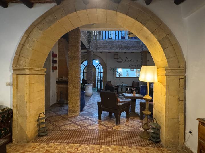 Atmospheric interior of a traditional riad featuring stone arches, tiled floors and cozy seating.