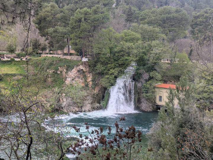 Gentle waterfall flowing into a turquoise pool surrounded by spring greenery.