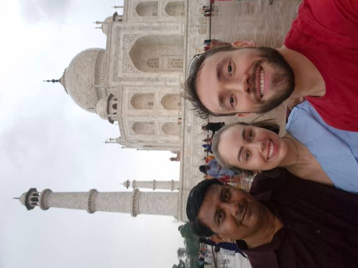 Smiling travellers taking a selfie in front of the Taj Mahal’s iconic marble dome.