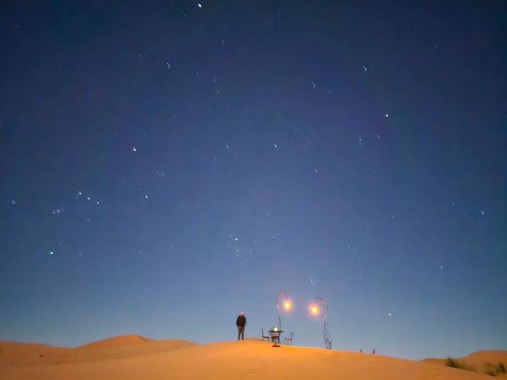 Night sky filled with stars above a lone figure in the quiet desert.