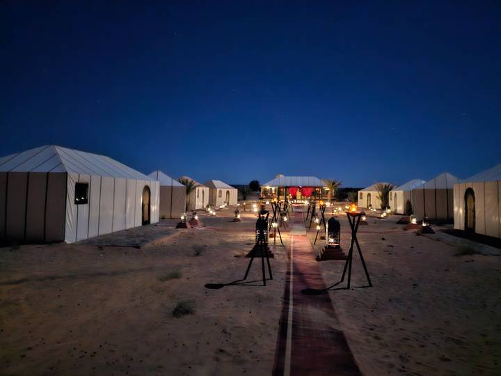 Luxury desert camp illuminated by lanterns under a clear starry night.