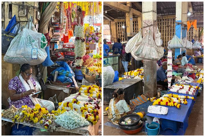 Busy flower market stalls with women threading garlands among colorful blooms.