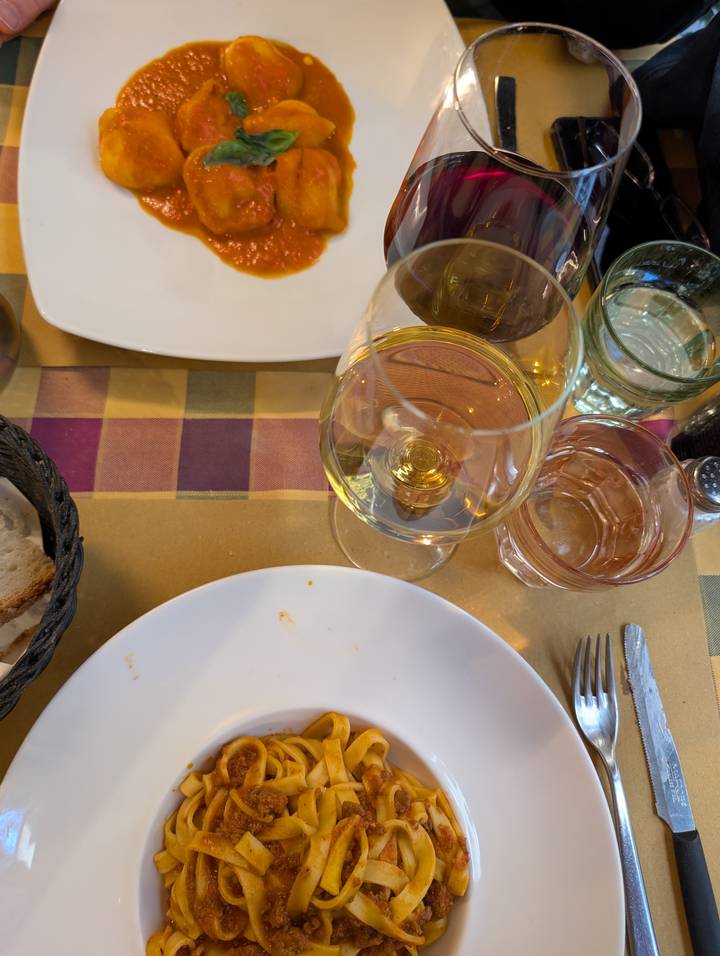 Tabletop view of partially finished meal with wine and bread at a rustic restaurant.