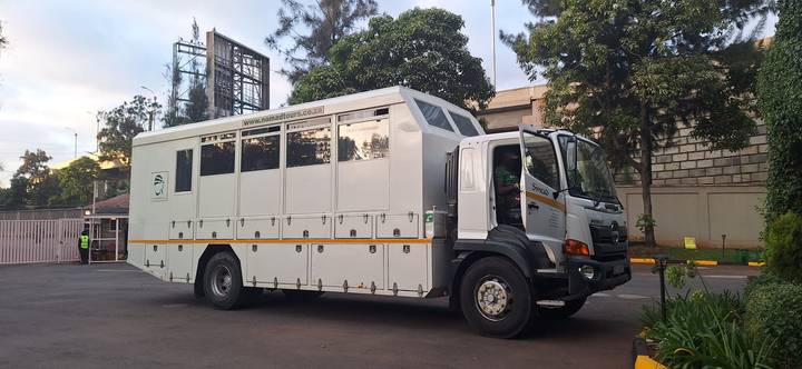 Large white overland safari truck parked outside a city compound, ready for an expedition