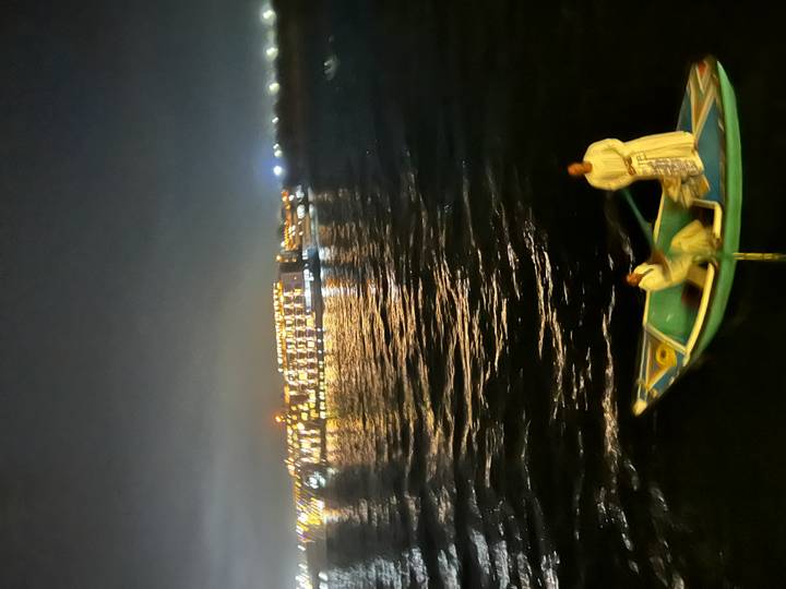 Blurry nighttime shot of two men in a small boat on the Nile with city lights behind.