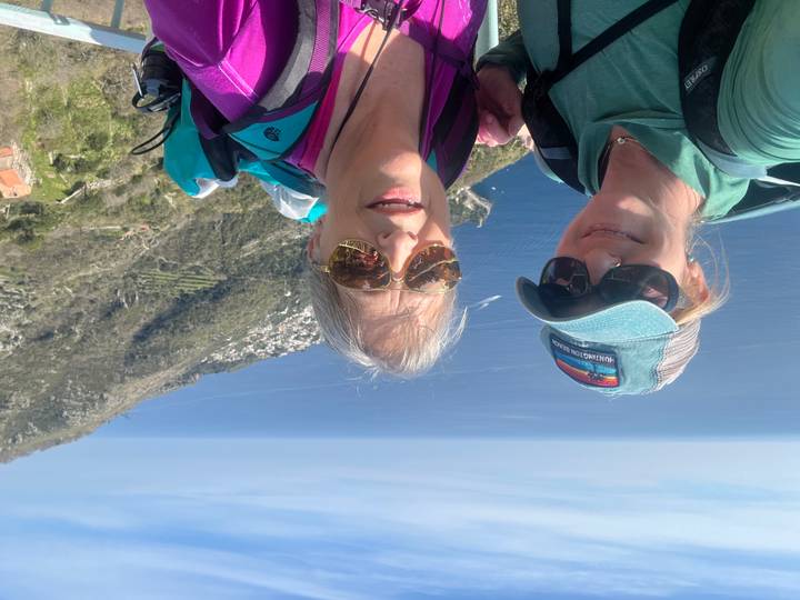 Selfie of two women with backpacks overlooking the Amalfi Coast and deep blue sea.