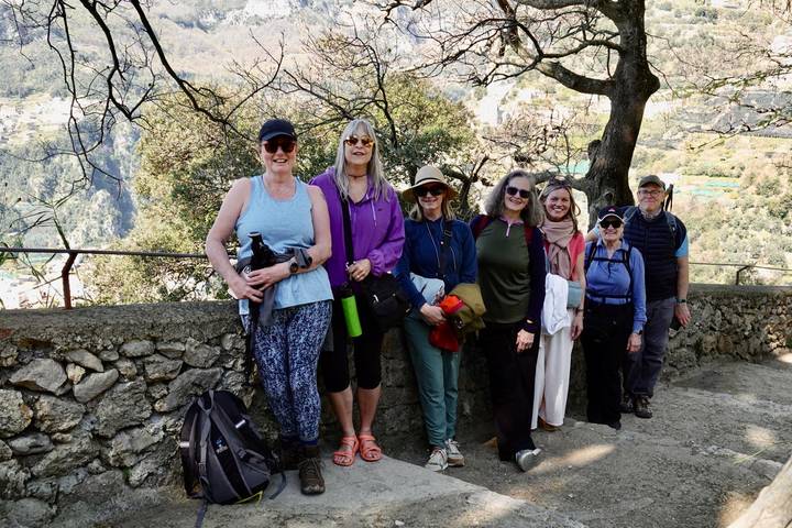 Small hiking group posing by a stone railing with forested valley behind.