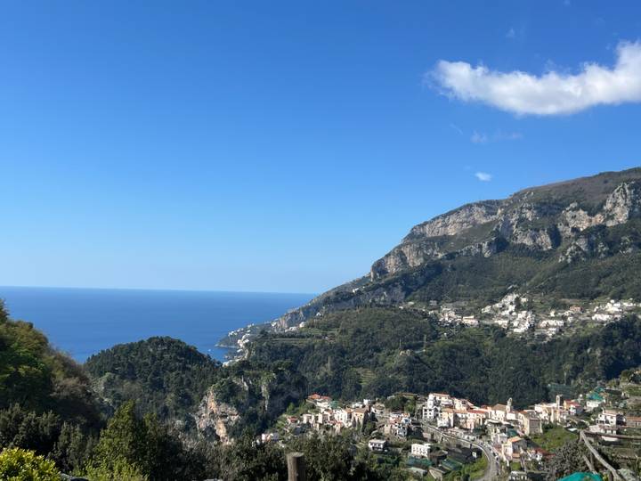 Wide coastal landscape of the Amalfi Coast with hillside villages and deep blue sea under a clear sky.