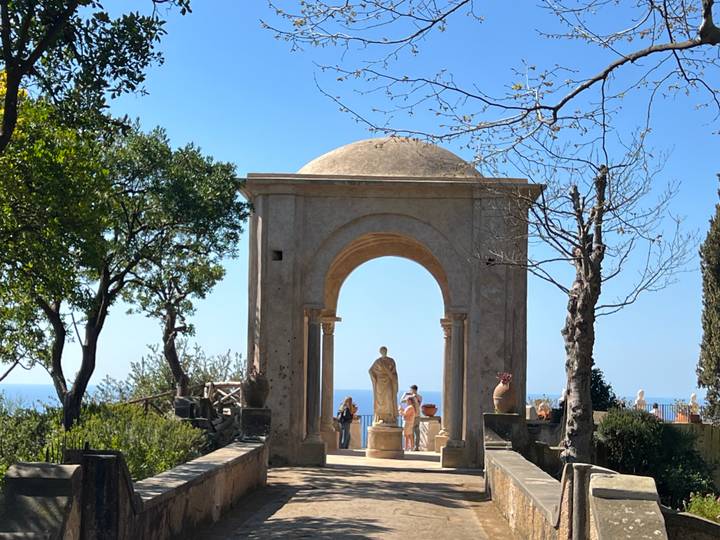 Stone arch pavilion and garden statue overlooking the sea at Villa Cimbrone.