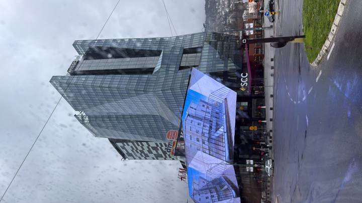 Modern glass tower complex in Sarajevo seen through a rain-spattered window on a gray day.