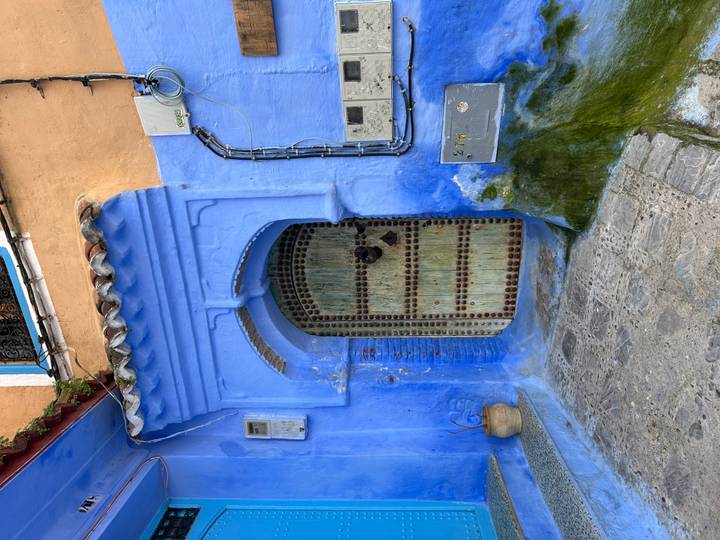 Traditional arched blue doorway with aged wooden door and mosaic studs.