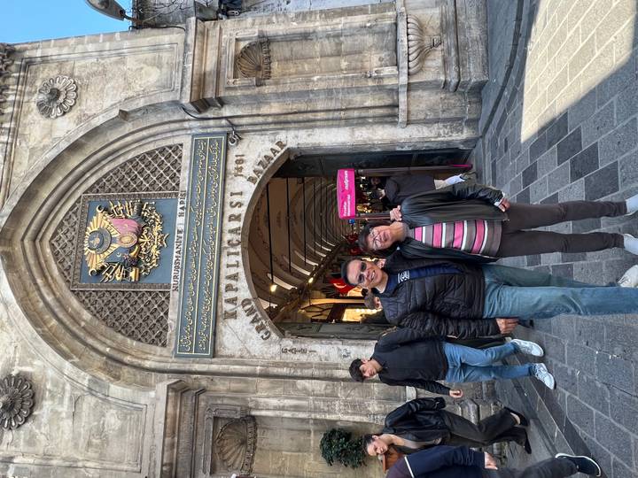 A pair of tourists pose beneath the ornate entrance of the Grand Bazaar.