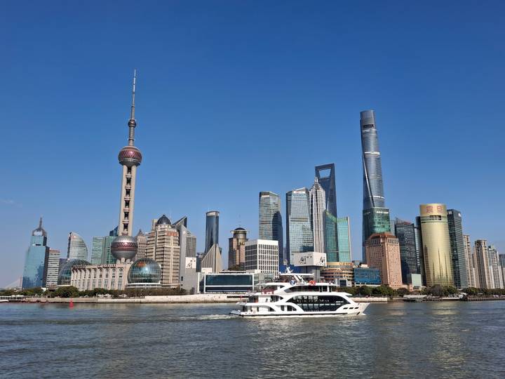 Iconic Shanghai Pudong skyline with Oriental Pearl Tower and modern skyscrapers above the Huangpu River with a passing white ferry.