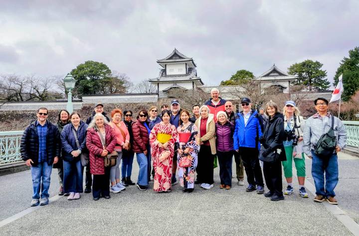 Group posing in front of Kanazawa Castle gate with cloudy sky