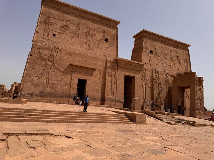 Visitors exploring monumental pylons with carved reliefs at Philae Temple