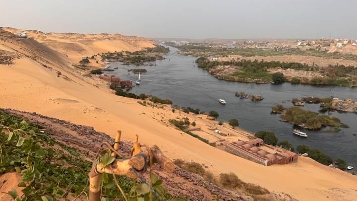 Panoramic view of the Nile River winding past sandy dunes and green islands near Aswan