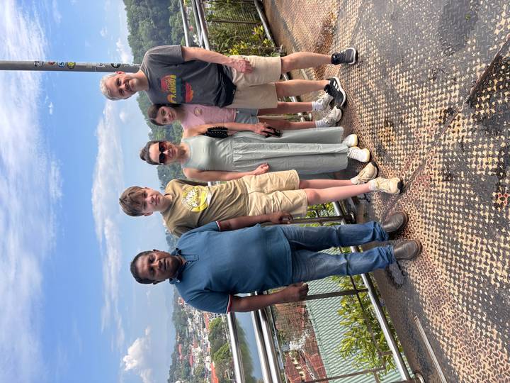 Family with guide stands on a viewing platform overlooking a hilly cityscape