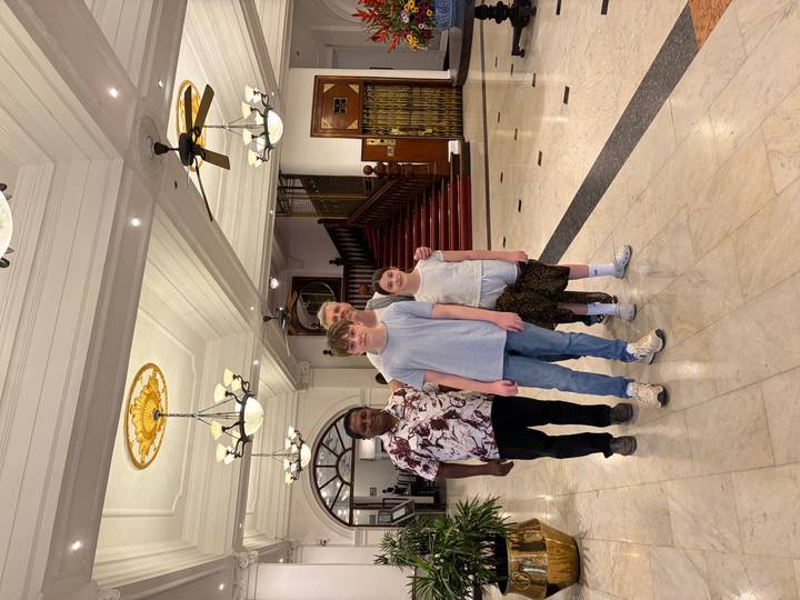 Family with driver poses in an elegant hotel lobby with marble floors and staircase