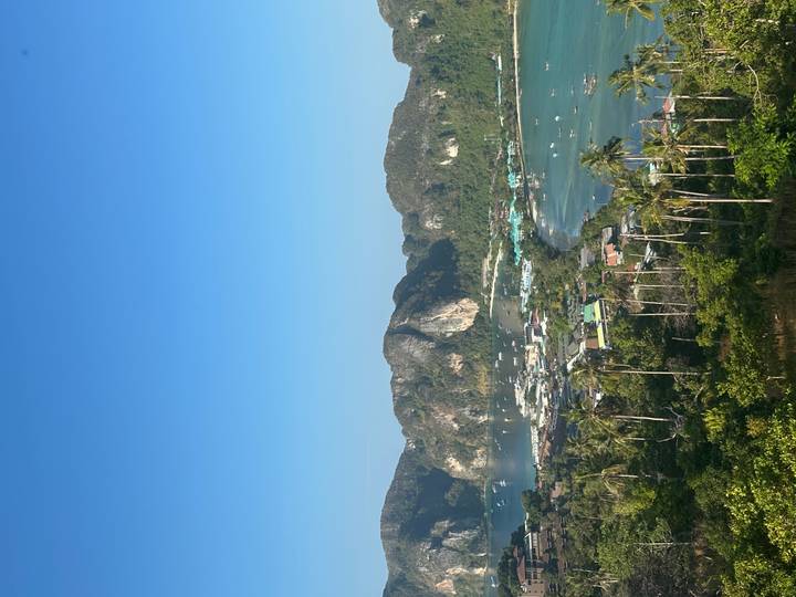 High viewpoint overlooks twin turquoise bays and jungle-covered limestone cliffs on a sunny morning.