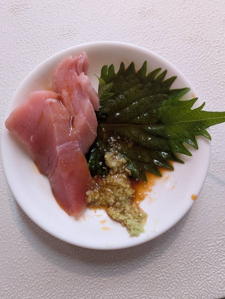 Plate of fresh tuna sashimi with grated ginger, soy sauce and shiso leaves