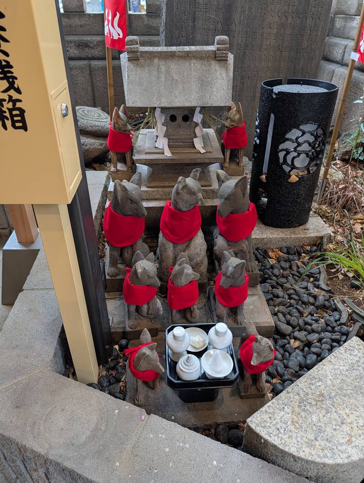 Row of stone fox statues wearing red bibs at a Shinto shrine
