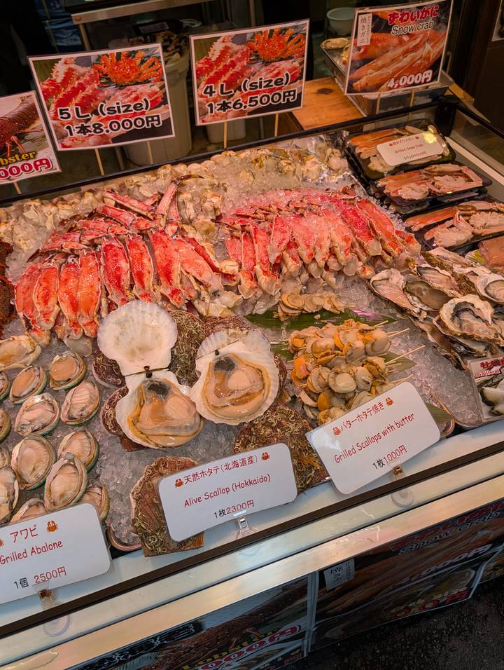 Display of fresh seafood on ice including scallops, crab legs and abalone with price signs